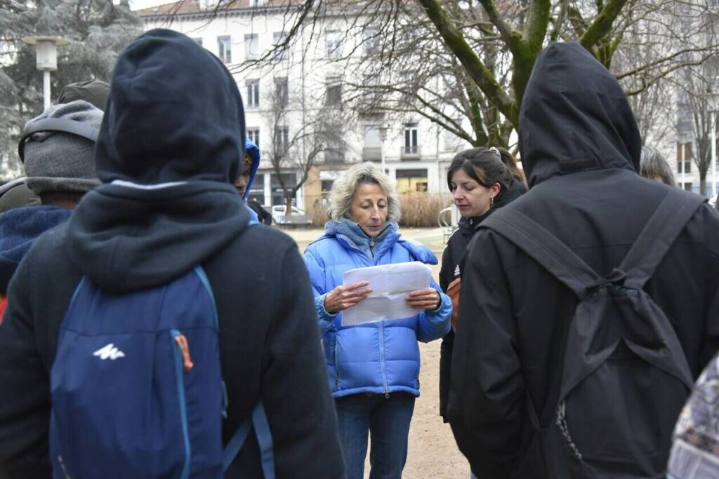 Diane Etchart (en bleu), riveraine et militante, rassure les jeunes migrants, inquiets de savoir où et s’ils seront mis à l’abri. | MORGANE REMY